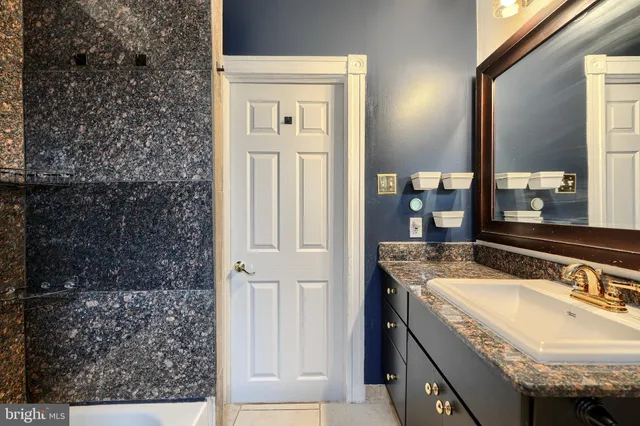 a bathroom with a granite countertop sink a mirror and shower