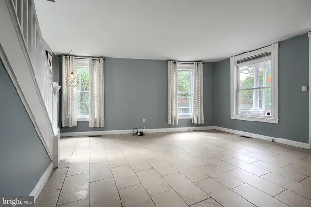 a view of an empty room with window and chandelier fan