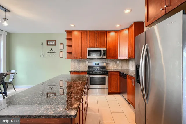 a kitchen with stainless steel appliances granite countertop a refrigerator sink and stove