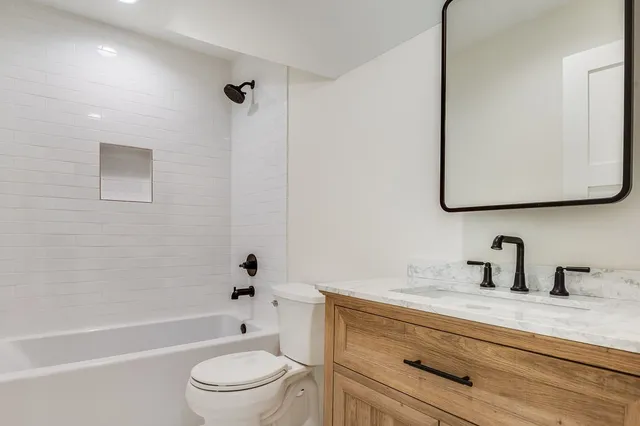 a bathroom with a bathtub shower sink vanity and toilet
