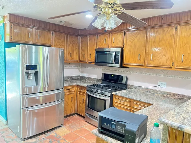 a kitchen with stainless steel appliances granite countertop a refrigerator a stove top oven a sink and dishwasher