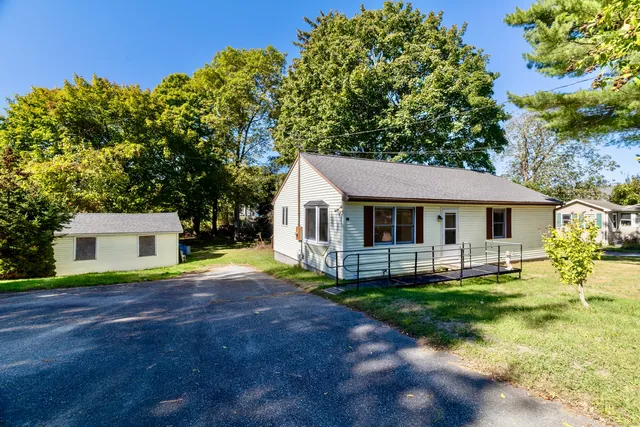a front view of a house with a yard and trees