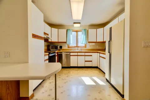 a kitchen with stainless steel appliances granite countertop a sink a stove a refrigerator with white cabinets and wooden floor