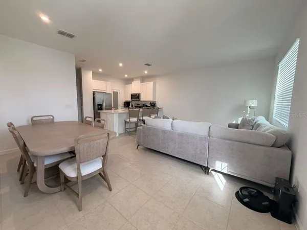 a living room with furniture and a dining table with kitchen appliances