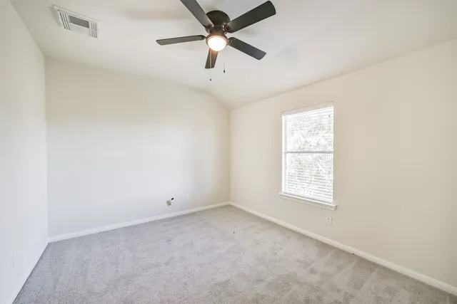 an empty room with a ceiling fan and a window