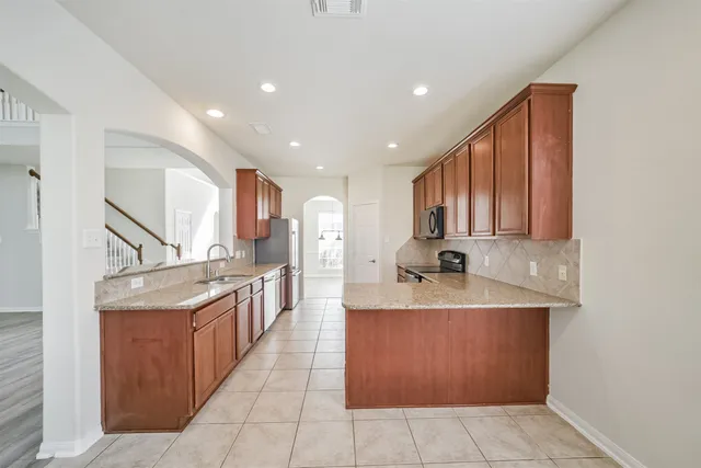 a kitchen with stainless steel appliances granite countertop a sink and a refrigerator