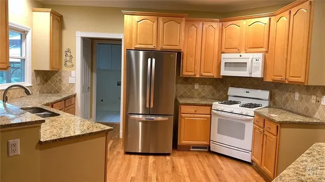 a kitchen with granite countertop wooden floors and stainless steel appliances