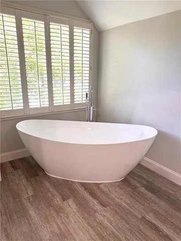 a white tub sitting in a bedroom next to a window