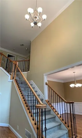 a view of staircase with railing and a chandelier