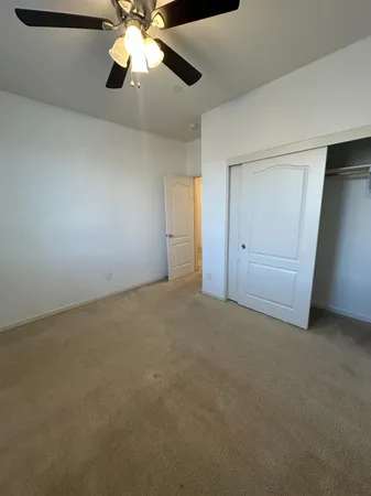 an empty room with closet and a chandelier fan