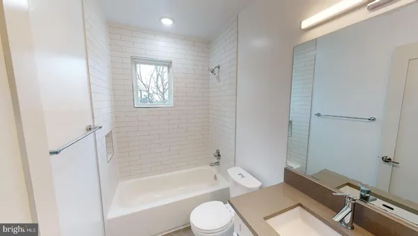 a bathroom with a granite countertop bathtub shower sink vanity and toilet