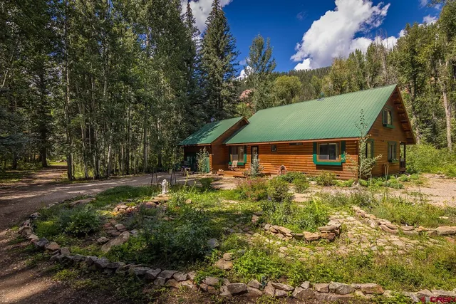 a view of a house with a yard and large tree