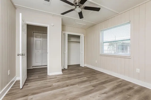 a view of an empty room with window and wooden floor