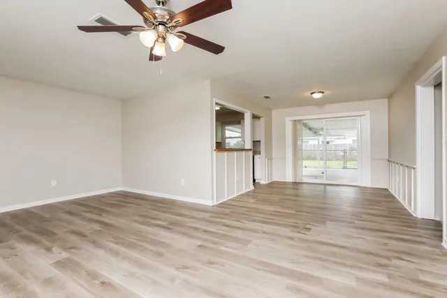 a view of an empty room with window and wooden floor