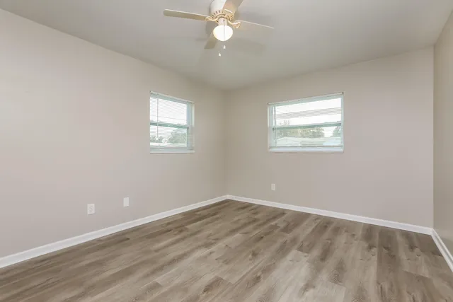 an empty room with wooden floor and windows