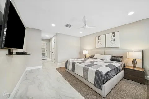 a bedroom with a large bed and a flat tv screen on dresser