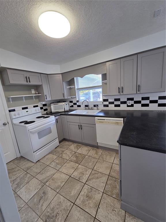 298 11th Avenue Southwest Largo, FL 33770 - Photo 12 of 34 a kitchen with stainless steel appliances granite countertop a sink stove refrigerator and cabinets
