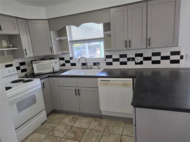 a kitchen with a sink dishwasher stove and white cabinets