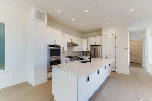 a kitchen with white cabinets and stainless steel appliances