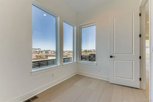 an empty room with wooden floor cabinet and windows