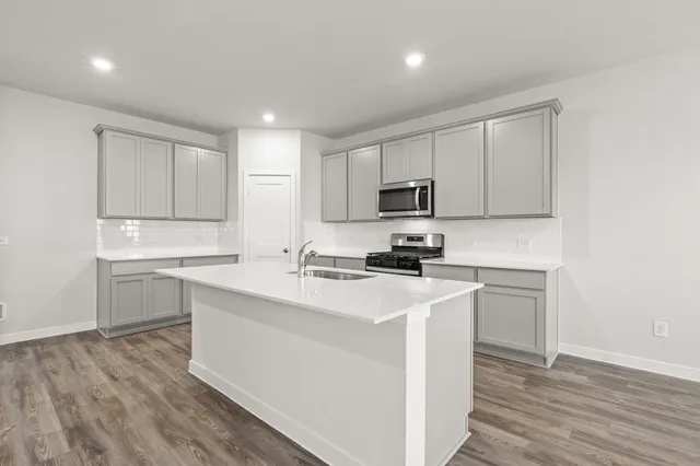 a kitchen with a sink a stove a refrigerator and white cabinets