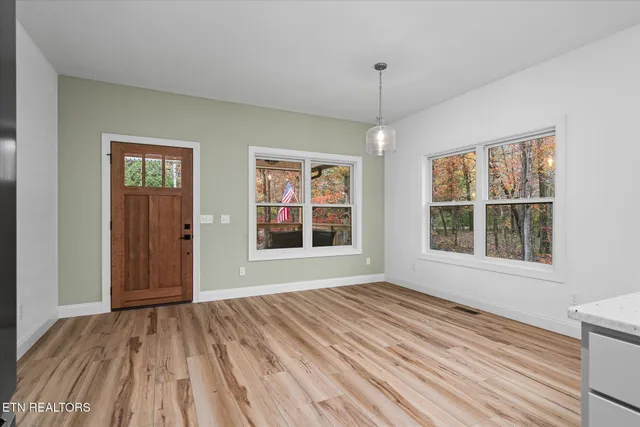 a view of an empty room with a window and wooden floor