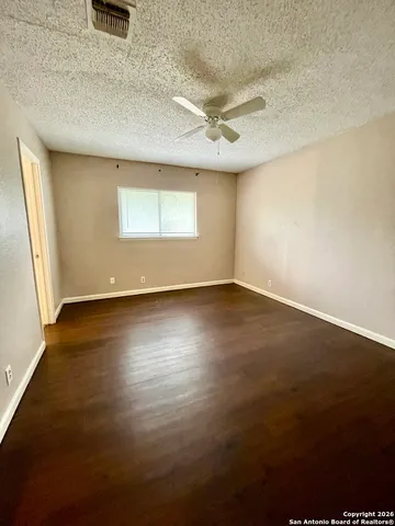 an empty room with wooden floor fan and windows