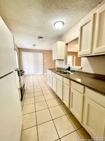 a kitchen with a sink a stove top oven and cabinetry