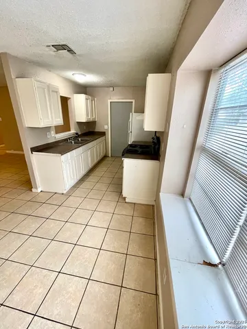 a kitchen with a sink a stove and white cabinets