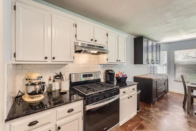 a kitchen with stainless steel appliances granite countertop a stove a sink dishwasher and cabinets with wooden floor