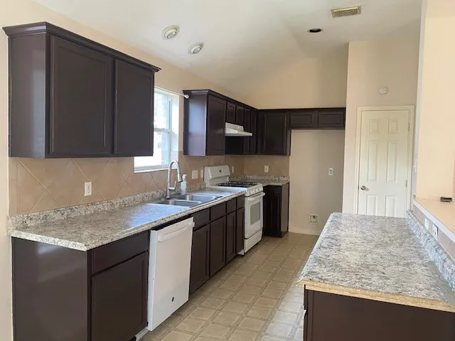 a kitchen with kitchen island granite countertop a sink stove and refrigerator