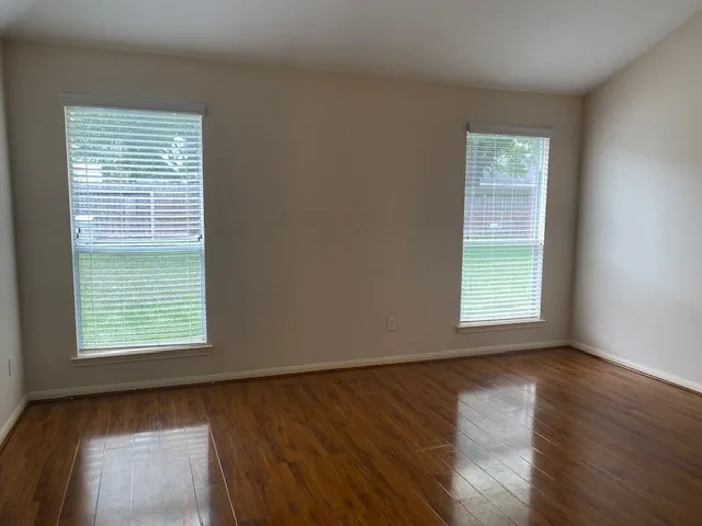a view of an empty room with wooden floor and a window
