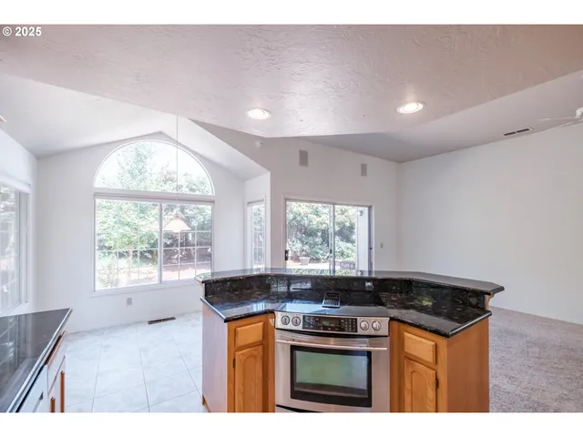 a kitchen with stainless steel appliances granite countertop a stove a sink and a granite counter tops with white cabinets