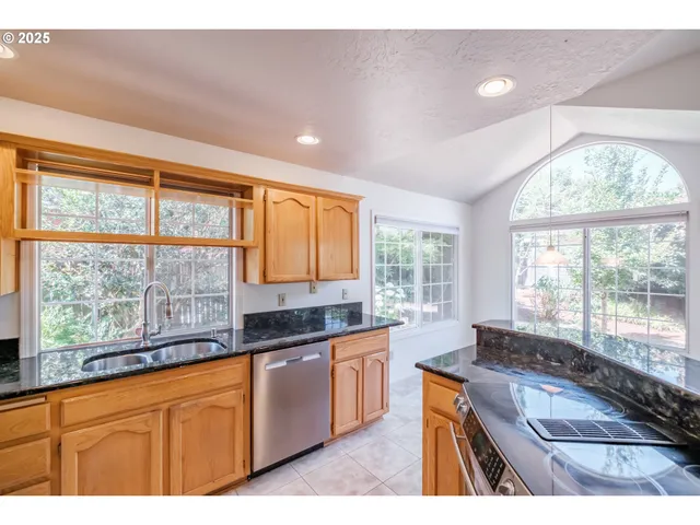 a kitchen with stainless steel appliances granite countertop a sink a stove and a large window