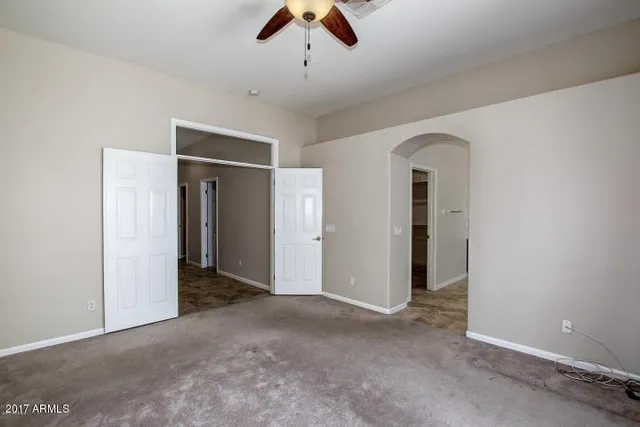 an empty room with ceiling fan and window