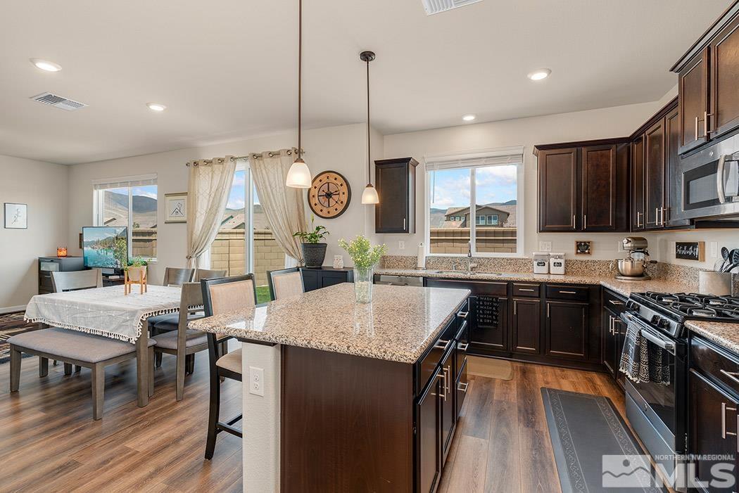 2395 Soprano Reno, NV 89521 - Photo 6 of 27 a kitchen with granite countertop a stove a sink a dining table and chairs with wooden floor