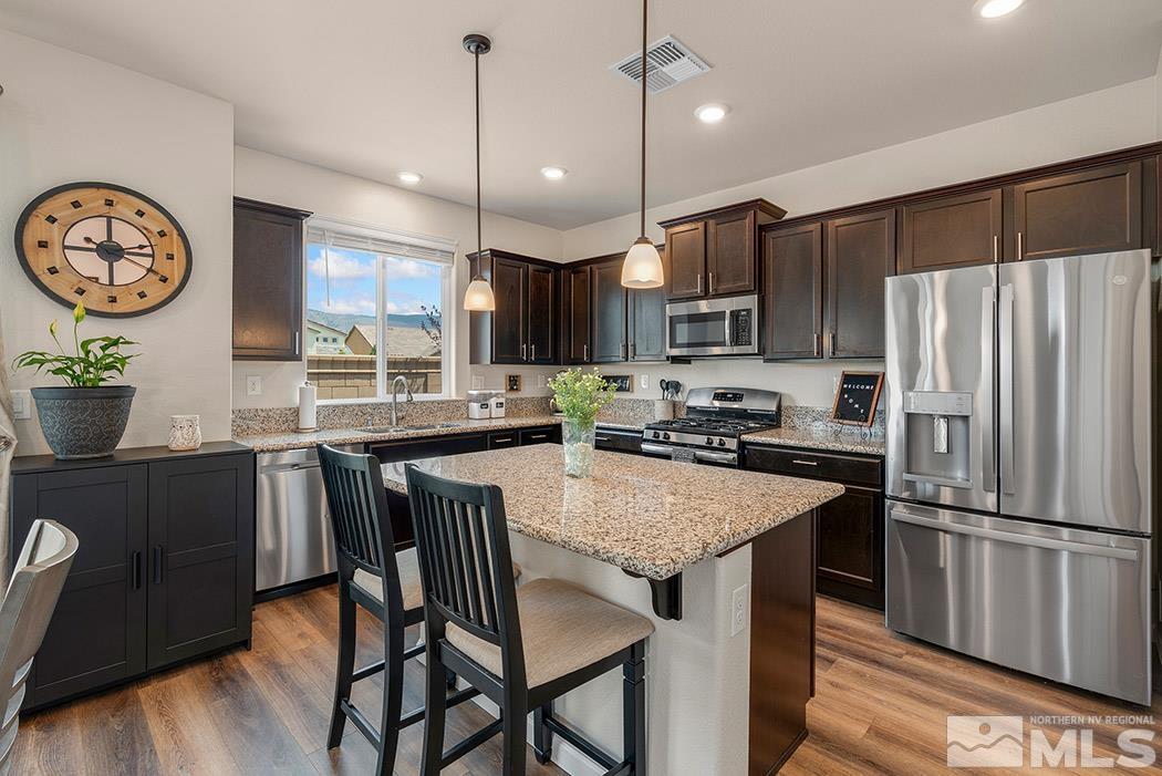 2395 Soprano Reno, NV 89521 - Photo 7 of 27 a kitchen with stainless steel appliances granite countertop a refrigerator a stove a sink dishwasher a dining table and chairs with wooden floor