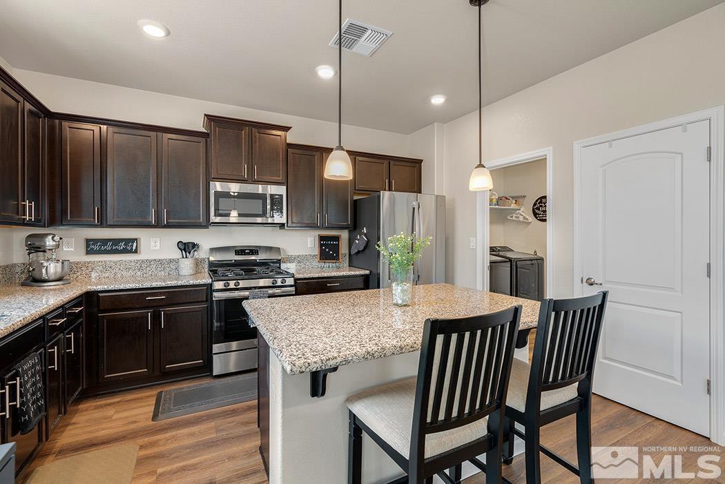 2395 Soprano Reno, NV 89521 - Photo 8 of 27 a kitchen with stainless steel appliances granite countertop a stove top oven a refrigerator a sink and chairs