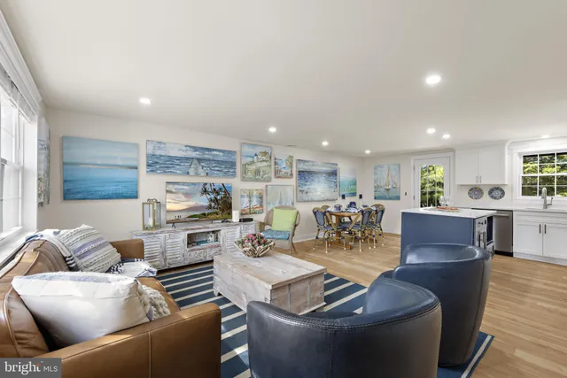 a kitchen with a stove a sink a counter top space and living room view