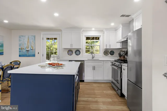 a kitchen with kitchen island stainless steel appliances a sink a stove a refrigerator and island