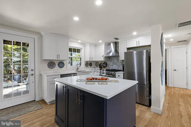 a kitchen with stainless steel appliances a refrigerator a stove a sink dishwasher and a dining table with wooden floor