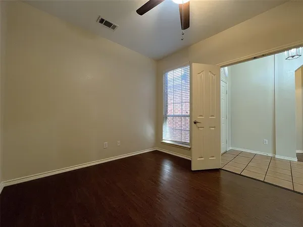an empty room with wooden floor cabinet and windows