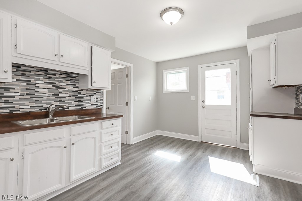 6665 State Road Cleveland, OH 44134 - Photo 11 of 30 Kitchen with decorative backsplash, sink, light wood-type flooring, and white cabinetry