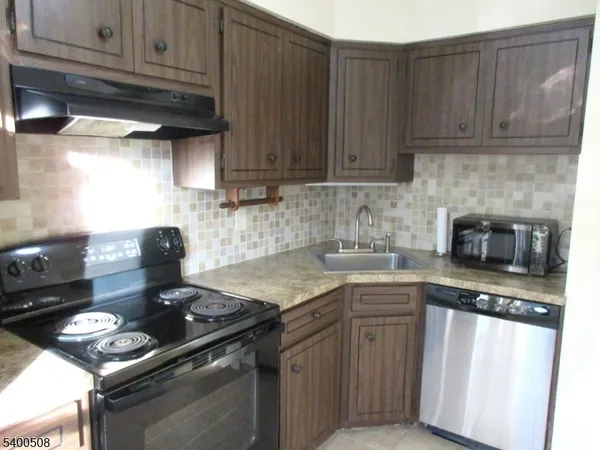 a kitchen with granite countertop stainless steel appliances wooden cabinets and a stove top oven