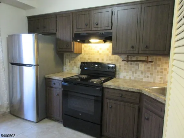 a kitchen with granite countertop a refrigerator stove and cabinets