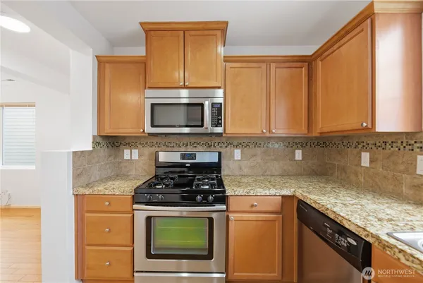 a kitchen with granite countertop a stove top oven microwave and cabinets