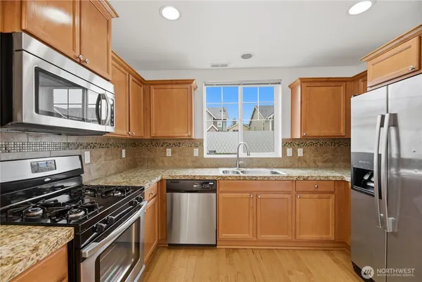 a kitchen with stainless steel appliances granite countertop a stove a sink dishwasher and a refrigerator