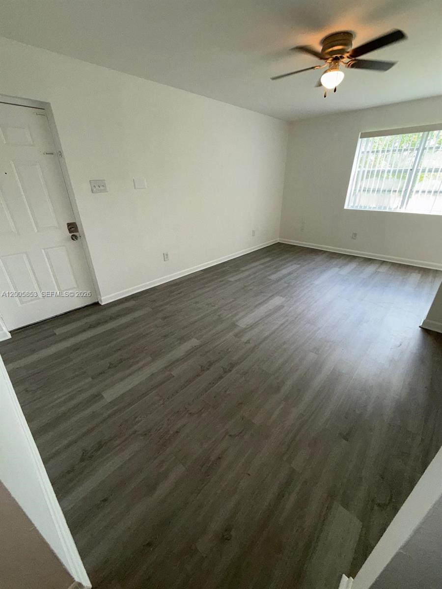 15285 Southwest 107th Lane, Unit 214 Miami, FL 33196 - Photo 4 of 16 an empty room with wooden floor ceiling fan and window