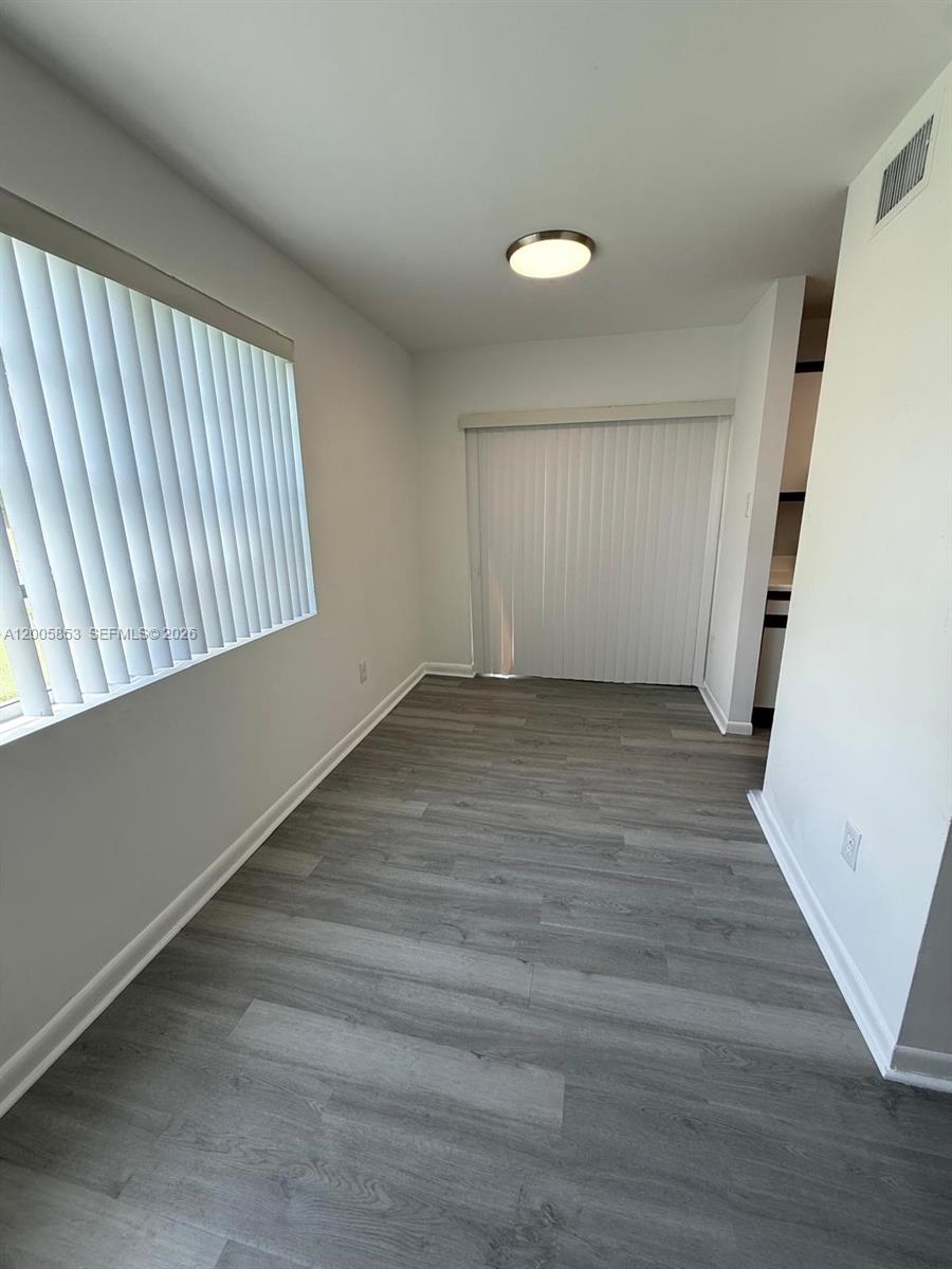 15285 Southwest 107th Lane, Unit 214 Miami, FL 33196 - Photo 6 of 16 an empty room with wooden floor and windows