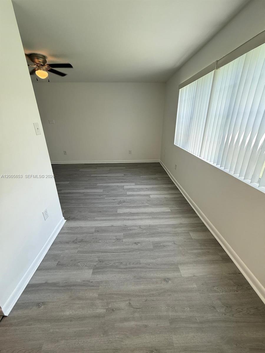 15285 Southwest 107th Lane, Unit 214 Miami, FL 33196 - Photo 7 of 16 a view of an empty room with wooden floor and a window